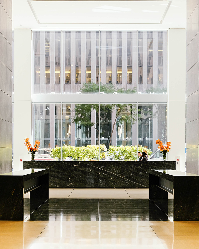 Grand ground floor lobby with grey marble walls and black marble concierge desk