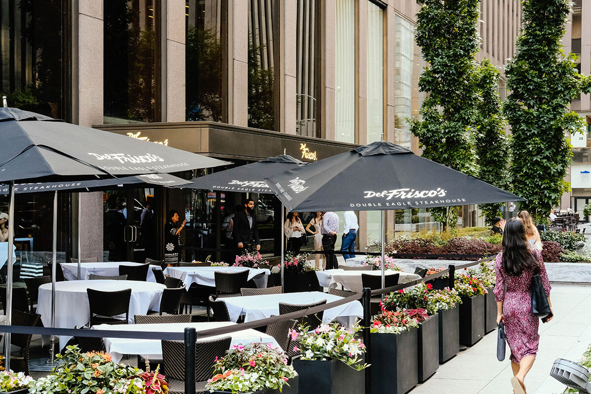 Sidewalk view of a city block with several of full flower gardens