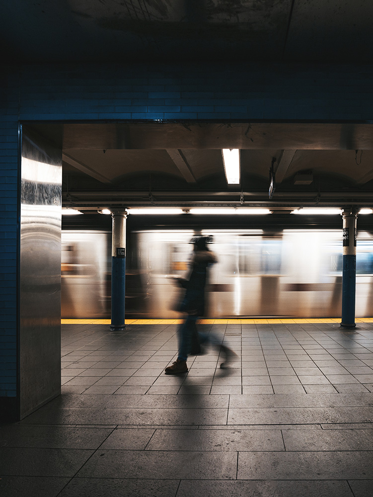 Motion blurred subway passenger walking by a running subway train
