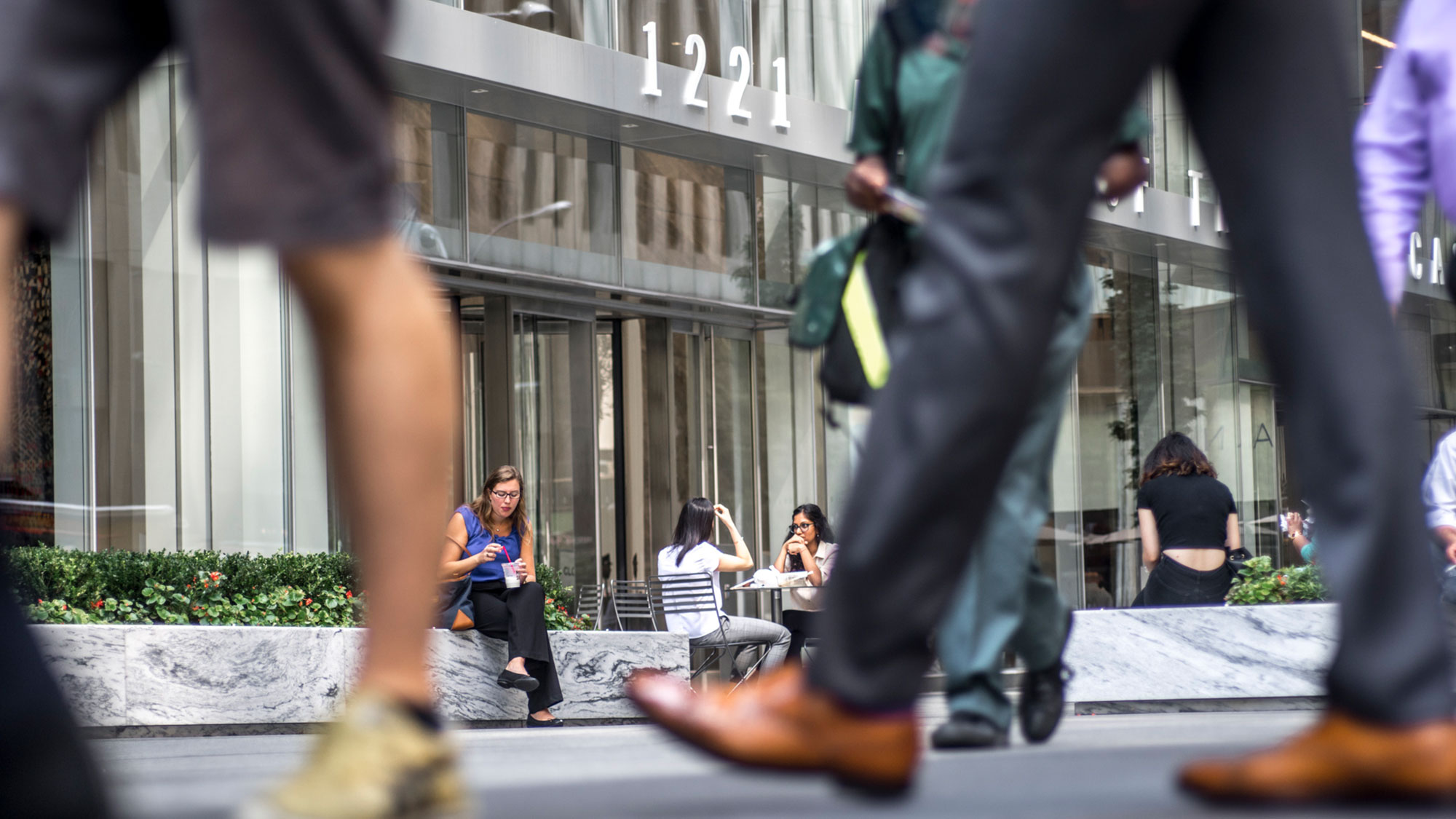 Sidewalk view of people sitting outside building 1221 in Midtown