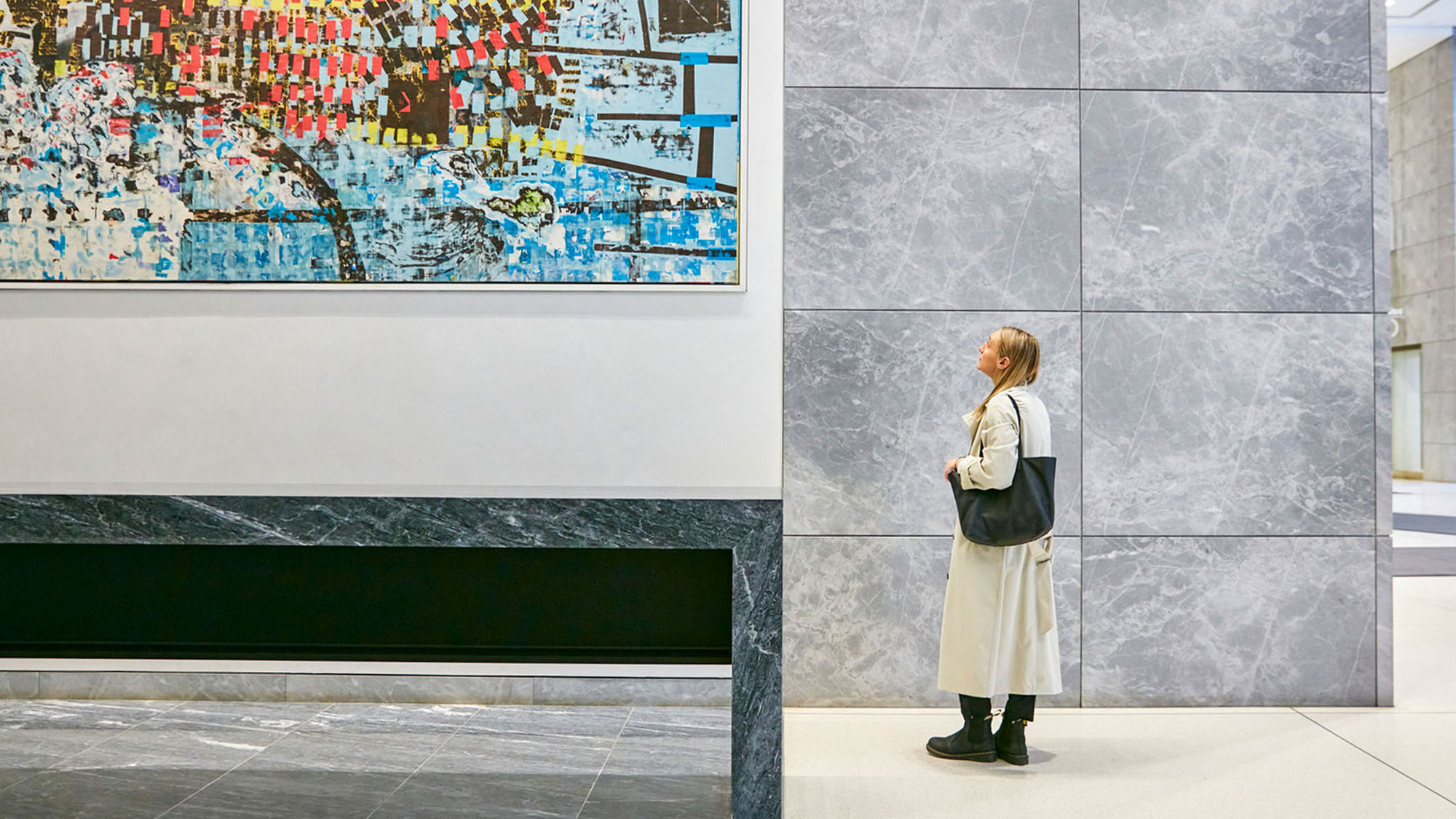 A woman wearing an overcoat gazing up at a big colorful art piece